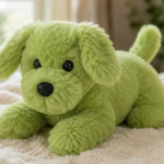 Ein grüner, flauschiger Plüschhund mit langen Schlappohren und schwarzer Nase liegt auf einer hellen, weichen Decke.